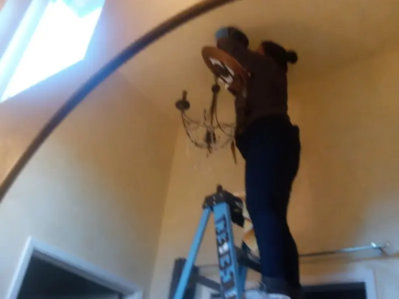 Electrician installing a chandelier in a Garrison residence